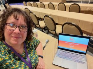 Pauline Lynch Shostack sitting at a table with a laptop.