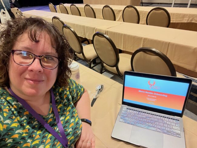Pauline Lynch Shostack at the Innovative User Group Conference Pauline Lynch Shostack sitting at a table with a laptop.